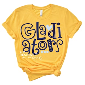 May include: Yellow t-shirt with the text "Gladiator" in blue with a blue heart and blue dots. The text "My Designs in the Chaos" is also in blue.