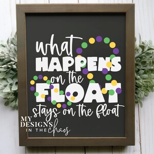 May include: Black chalkboard sign with white text that reads "what happens on the float stays on the float" with purple, green, and yellow Mardi Gras beads. The bottom of the sign reads "My Designs in the Chaos."