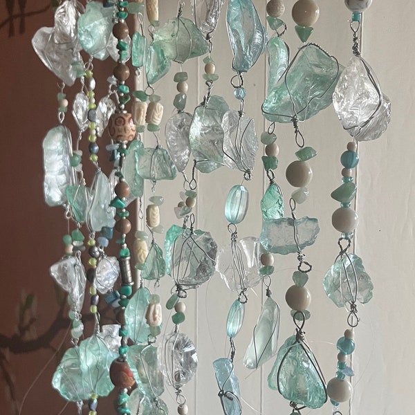 18” Teal/ sea foam colored Sea Glass strung w/ accentuating shell beads. Hung from swivel hook.