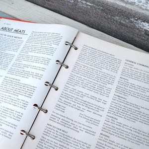 May include: An open cookbook with a yellow tab labelled "Salads/Vegetables" and a white tab labelled "Meats". The page is open to a section titled "General Cooking Methods" with instructions for roasting, browning, pan-broiling, pan-frying, and braising meat.