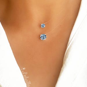 Pode incluir: Um colar delicado de duas camadas com duas correntes finas transparentes e dois pingentes de cristal azul claro. O pingente maior est&aacute; na parte inferior do colar e o pingente menor est&aacute; acima.