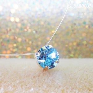 Pode incluir: Um colar delicado e transparente com um &uacute;nico pingente de cristal redondo azul claro.