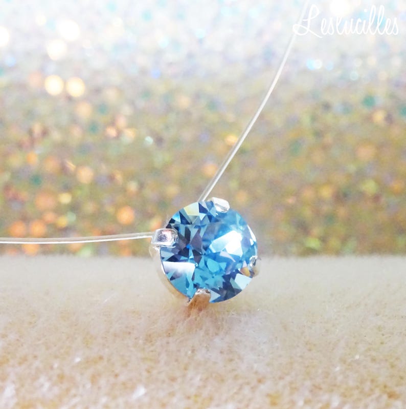 Pode incluir: Um colar delicado e transparente com um &uacute;nico pingente de cristal redondo azul claro.