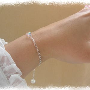 Peut inclure: Un bracelet délicat en chaîne argentée avec un charme en cristal transparent. La chaîne est fine et présente un design délicat. Le charme en cristal est iridescent et capte la lumière.