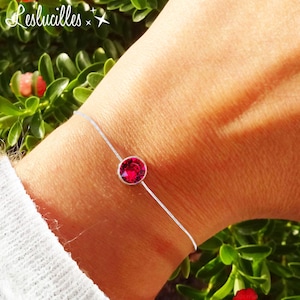 Könnte beinhalten: Ein filigranes Silberarmband mit einem leuchtenden, runden, roten Edelstein. Das Armband ist schlicht und elegant, wobei der Edelstein im Mittelpunkt steht. Der Text "Leslucilles" ist im Bild enthalten.