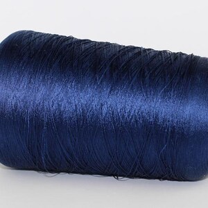May include: A dark navy blue thread spool. The thread is tightly wound, with a subtle sheen. The core of the spool is made of cardboard. This thread is suitable for sewing and craft projects. The thread is approximately 10 cm in length.