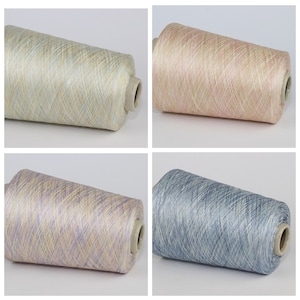 May include: Four spools of yarn in different colors: light blue, light pink, light purple, and light beige. Each spool has a white label.