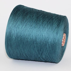 Può includere: Un gomitolo di filo blu turchese avvolto su un rocchetto di cartone.