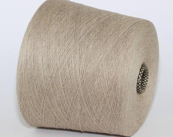 May include: A large spool of beige yarn, tightly wound and textured. The yarn appears to be a natural fibre, suitable for knitting or crocheting projects. The spool has a cylindrical shape with a central hole.