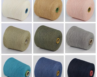 May include: Nine spools of yarn in different colours, including white, beige, pink, green, grey, blue, and navy. The spools are all the same size and shape, and they are arranged in a grid pattern.