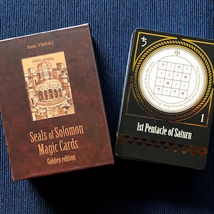 May include: A brown box with gold lettering that reads "Seals of Solomon Magic Cards Golden edition" and a black box with gold lettering that reads "1st Pentacle of Saturn" and a gold circle with Hebrew text and a number 5.