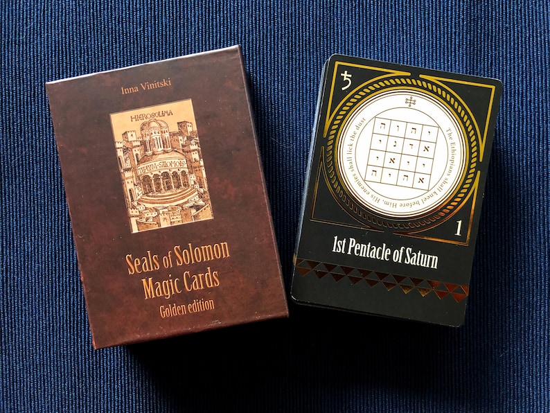 May include: A brown box with gold lettering that reads "Seals of Solomon Magic Cards Golden edition" and a black box with gold lettering that reads "1st Pentacle of Saturn" and a gold circle with Hebrew text and a number 5.