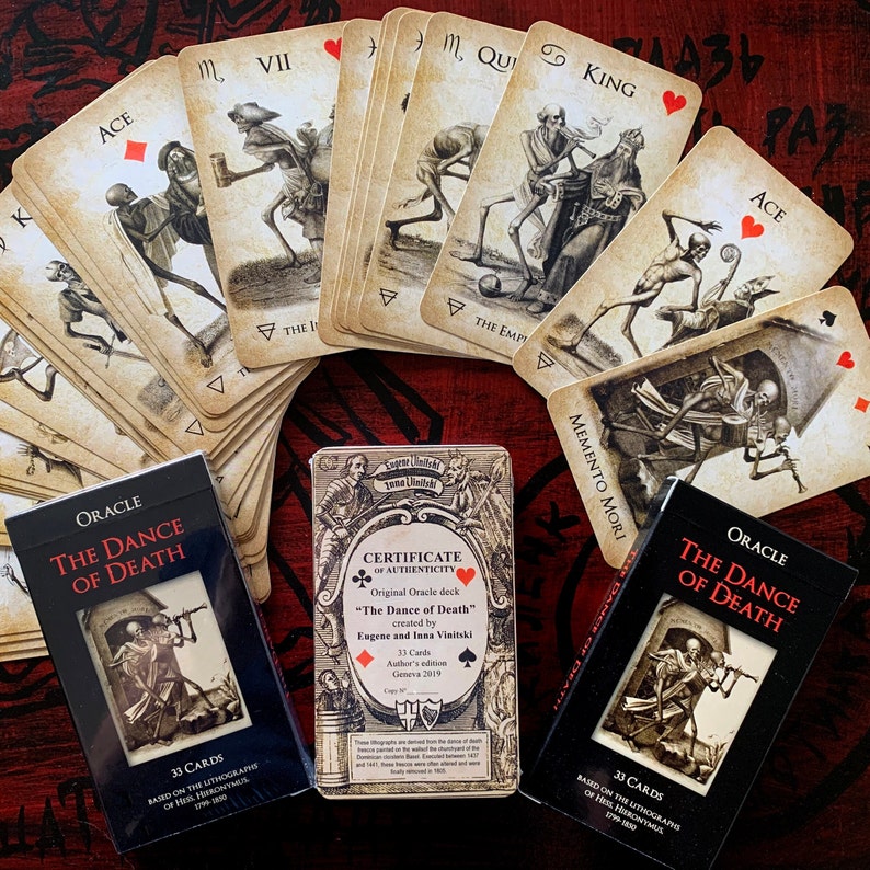 May include: An oracle deck titled "The Dance of Death" with 33 cards, featuring illustrations of skeletons. The deck includes a certificate of authenticity and is based on lithographs from 1799-1800. The cards are arranged in a fan shape.