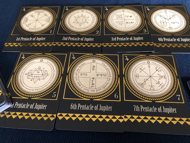 May include: Seven cards with gold trim and black backgrounds. Each card features a different symbol in a circle with Hebrew text. The cards are numbered 1 through 7 and labeled "Pentacle of Jupiter".