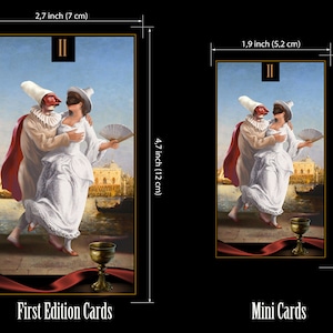 May include: Two figures in masquerade costumes, a man and a woman, dance in front of a Venetian cityscape. The man wears a red and white costume with a mask, and the woman wears a white dress with a mask. A golden chalice sits on a red ribbon in the foreground. The card is labeled "II" in the top left corner. The card measures 2.7 inches by 4.7 inches.