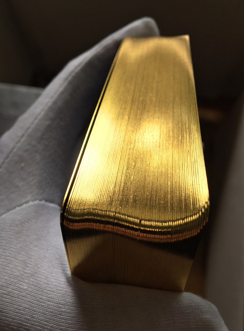 May include: A close-up of a stack of gold-colored playing cards. The cards are arranged in a neat, even stack, and the edges of the cards are visible.