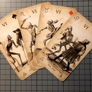 May include: A collection of vintage-style tarot cards, each featuring a skeletal figure in various poses. The cards are numbered with the Roman numeral VI and include suit symbols and astrological signs. The card titled "THE JEW" is visible.