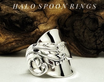 Op de afbeelding: Zilveren lepelsring met een decoratief bloemmotief. HALO SPOON RINGS staat op de achtergrond.