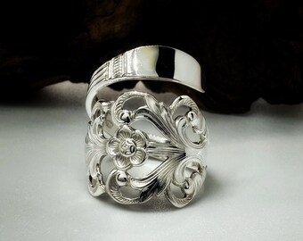 Op de afbeelding: Een zilveren lepelsring met een bloemmotief. De ring is gemaakt van een vintage lepel en heeft een halo-ontwerp. De ring is een uniek en stijlvol sieraad.