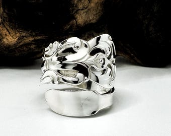 Op de afbeelding: Een zilveren lepelsring met een decoratief ontwerp. De ring is gemaakt van een hergebruikte lepel en heeft een unieke, handgemaakte uitstraling.