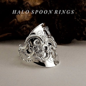 May include: A silver spoon ring featuring an intricate floral design. The ring is crafted from a vintage spoon and has a distinctive, handmade appearance.