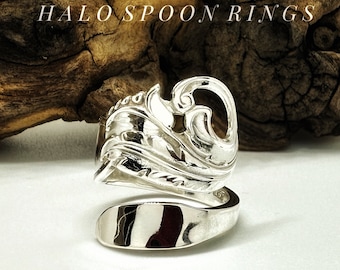 Op de afbeelding: Een zilveren lepelring met een sierlijk, wervelend ontwerp. De ring is gemaakt van een lepel en heeft een decoratieve bovenkant met een gebogen, open ontwerp. De tekst "HALOSPOON RINGS" staat bovenaan de afbeelding.