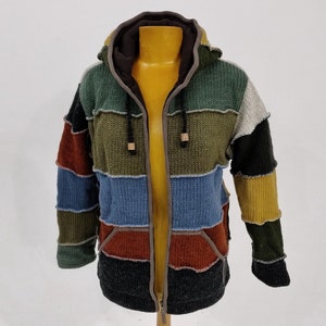 May include: A multi-coloured striped hooded sweater with a zip closure. The sweater is made of a knitted fabric and has a patchwork design.