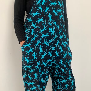 May include: Black overalls with a blue lizard print. The overalls have adjustable straps and two large pockets.