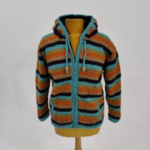 May include: A striped hooded sweater with a zipper closure. The sweater is made of a soft, knitted fabric and features a variety of colors, including teal, orange, brown, and black.