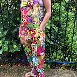 May include: A pair of colourful patchwork dungarees with a variety of floral and geometric patterns. The dungarees have a wide leg and are made of a lightweight fabric.