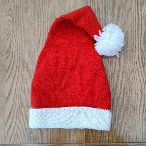 May include: A red knitted Santa hat with a white pom-pom and a white brim.