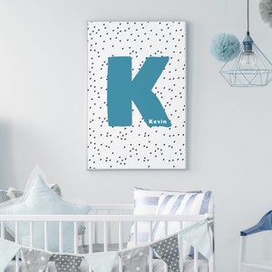 May include: A white canvas print with a blue letter K and the name Kevin in black text. The background is a white canvas with a black polka dot pattern.