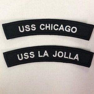May include: Two black embroidered patches with white lettering. The top patch reads "USS CHICAGO" and the bottom patch reads "USS LA JOLLA".