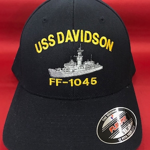 May include: A black baseball cap with a yellow embroidered USS DAVIDSON FF-1045 logo and a white embroidered ship illustration. The cap has a black Flexfit label on the side.