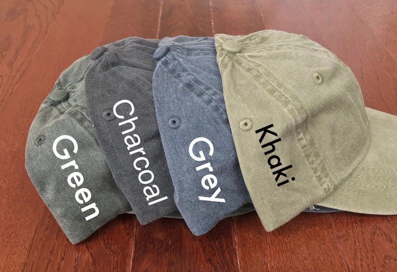 K&ouml;nnte beinhalten: Vier Baseballkappen in verschiedenen Farben: Gr&uuml;n, Anthrazit, Grau und Khaki. Die Kappen sind in einer Reihe angeordnet, wobei die gr&uuml;ne Kappe links und die Khaki-Kappe rechts ist.