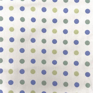 May include: White fabric with a repeating pattern of blue, green, and light green polka dots. The dots are evenly spaced across the surface, creating a playful and simple design. This fabric is suitable for various sewing and crafting projects.