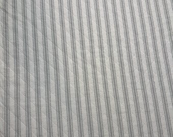 May include: White fabric with gray vertical stripes. The fabric has a quilted texture.