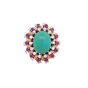 May include: A ring with a large green gemstone surrounded by a halo of smaller diamonds and red rubies.