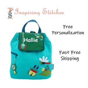 May include: A turquoise quilted backpack with a green flap featuring the name "Hallie". The backpack has a blue handle and is decorated with embroidered insects. A small charm with the text "Cute as a bug" hangs from the zipper.