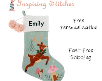 May include: A Christmas stocking with a forest theme, featuring a deer, mushrooms, and trees. The stocking is light green with a white cuff and pink pom-poms. The name "Emily" is embroidered on the cuff. The text "Inspiring Stitches" is at the top.