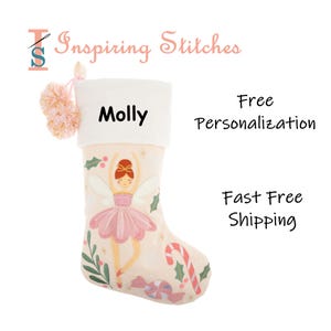 May include: A cream-colored Christmas stocking with a ballerina design, the name "Molly" is printed on the white cuff. The stocking features a pink tutu, wings, and a candy cane. A pink pom-pom hangs from the top.