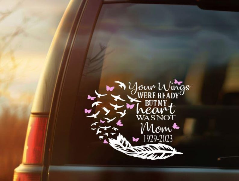 May include: A white vinyl decal with the text "Your Wings Were Ready But My Heart Was Not Mom 1929-2023" and a design of birds, butterflies, and a feather. The decal is applied to a vehicle window.