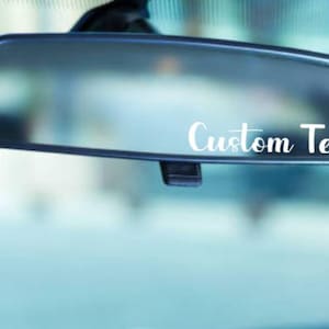 May include: A rearview mirror with a white vinyl sticker that says "Custom Text" on it.