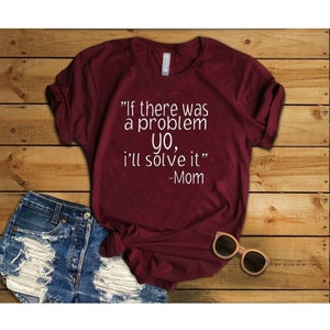 May include: Burgundy t-shirt with white text that reads "If there was a problem yo, I'll solve it" -Mom.