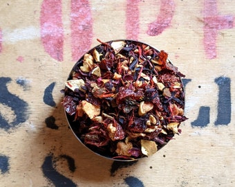 May include: A close-up of a bowl filled with a blend of dried fruit, flowers, and herbs. The mixture is a vibrant mix of red, orange, and brown hues.