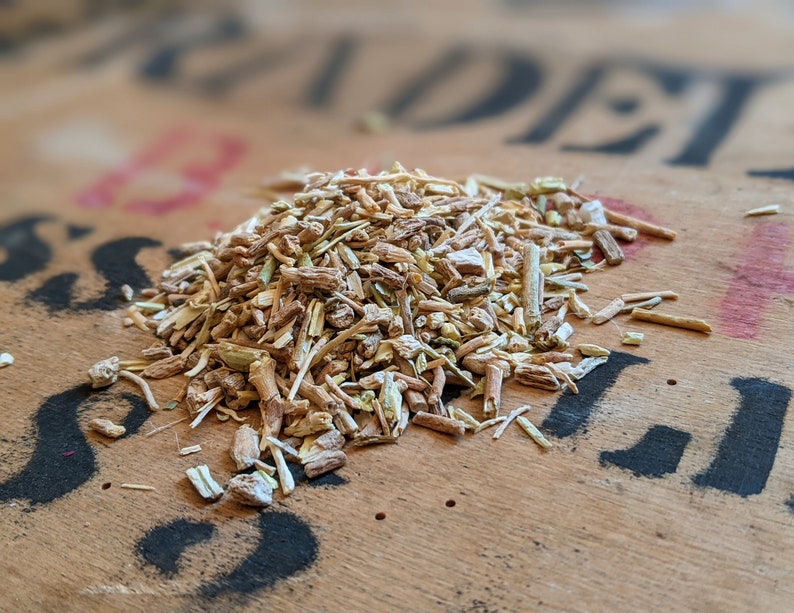 May include: A close-up of a pile of dried herbs, likely for tea or herbal remedies. The herbs are a mix of light brown, beige, and green, and appear to be finely chopped or shredded.