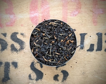 May include: A close-up of a small bowl filled with loose black tea leaves. The tea leaves are a mix of black tea and orange peel.