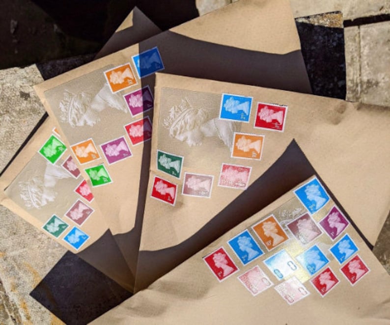 May include: Three brown envelopes with colorful stamps featuring a portrait of a woman. The stamps are arranged in a pattern on the envelopes.