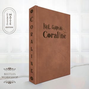minimalist vegan leather hardcover of Coraline by Neil Gaiman front view,
custom rebound Coraline book aesthetic brown matte cover with button detail
