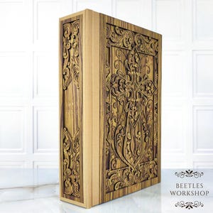 Könnte beinhalten: Ein dekoratives Holzbuch mit aufwendig geschnitzten floralen Mustern. Der Einband und der Buchrücken weisen detaillierte Muster auf, wobei der Text "LORD'S BIBLE" auf dem Buchrücken zu sehen ist. Das Buch hat eine warme braune Farbe und eine strukturierte Oberfläche.